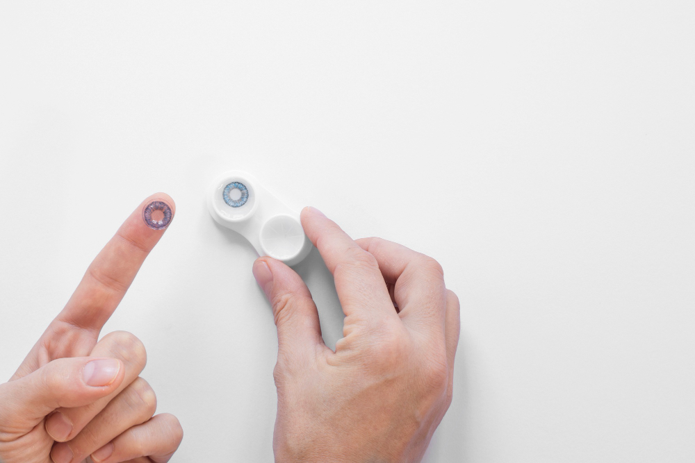 Fingers holding a contact lens